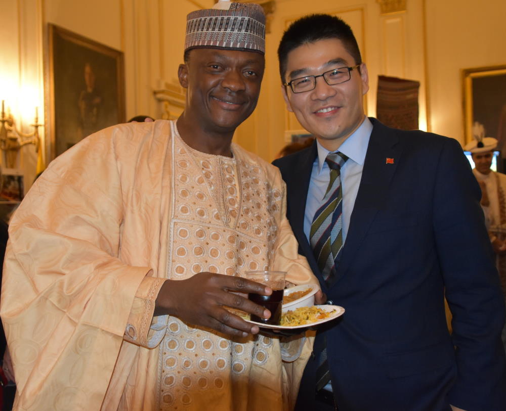 Two gentlemen smiling at camera, one in traditional dress robes and the other in a business suit