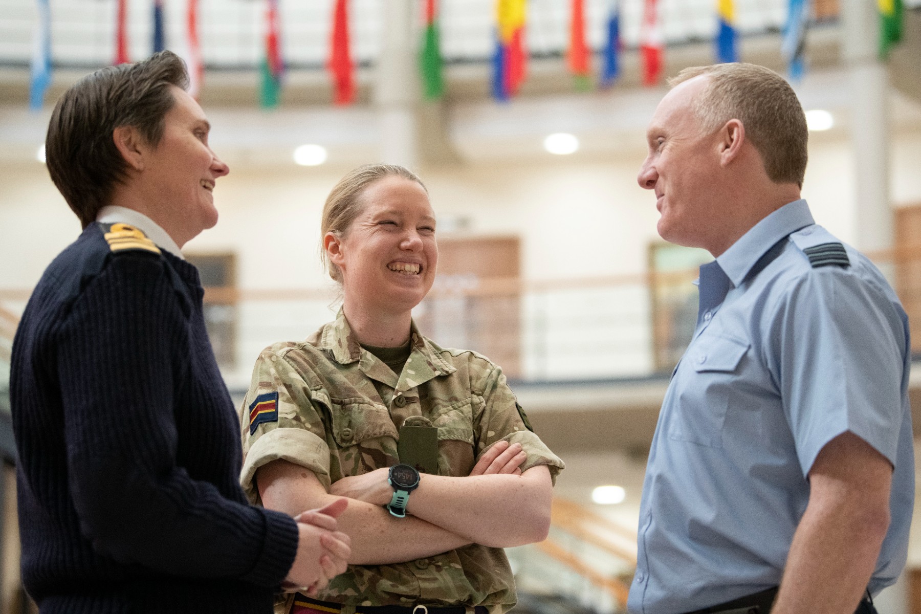 Three people in RAF, Navy and Army uniform smiling and talking in a small group