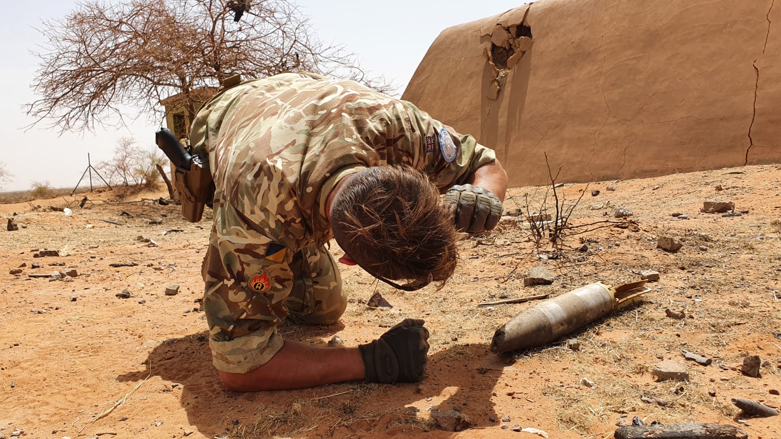 An Army officer led on ground checking weapon shell. 