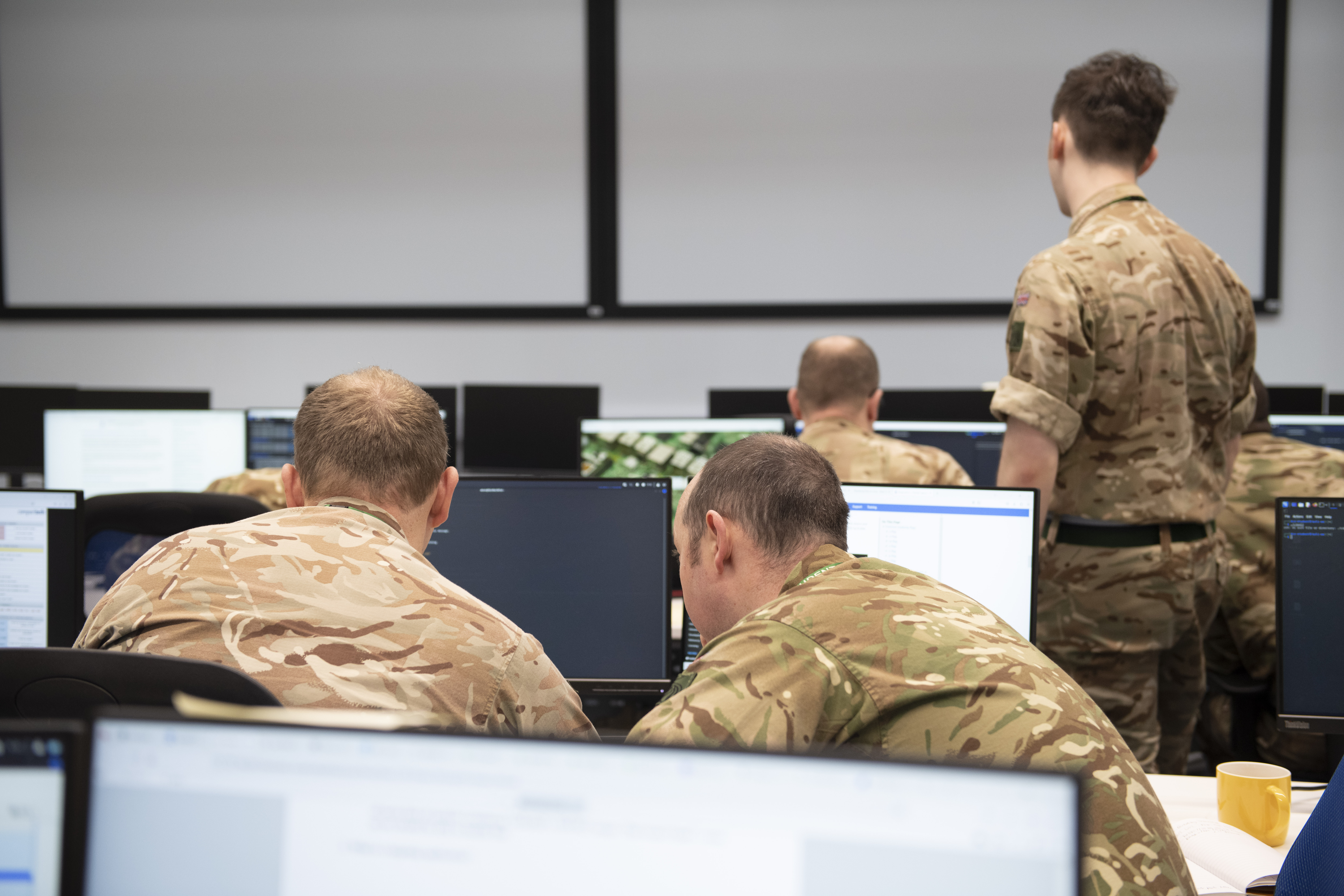 Army personnel looking at laptops working on a cyber challenge.