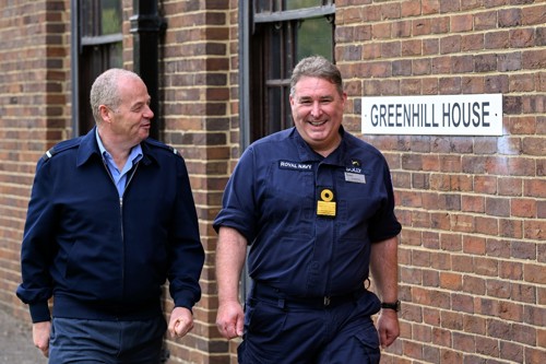 An RAF and RN officer walking past a building named 'Greenhill house'.