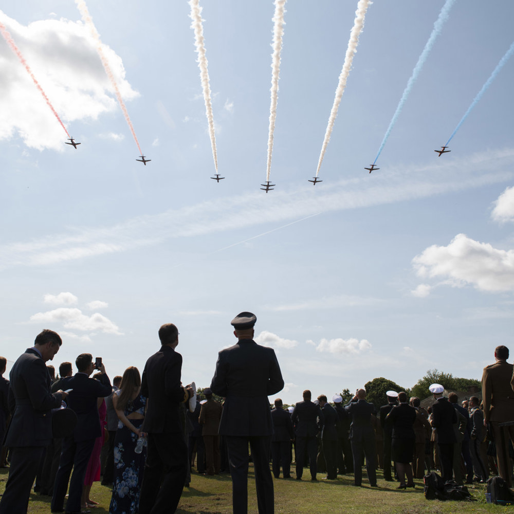 Red Arrows flying overhead with Defence Academy personnel observing.