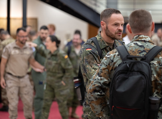 A German military officer talking to another officer with further group of officers out of focus in the background. 