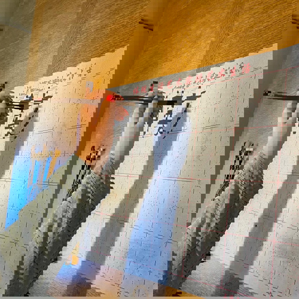 A hand using a paint brush to write Chinese symbols.