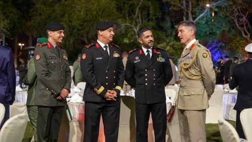 International dinner attendees in military uniform stood talking.