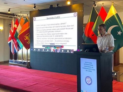 Major General Roe giving a presentation surrounded by international flags.