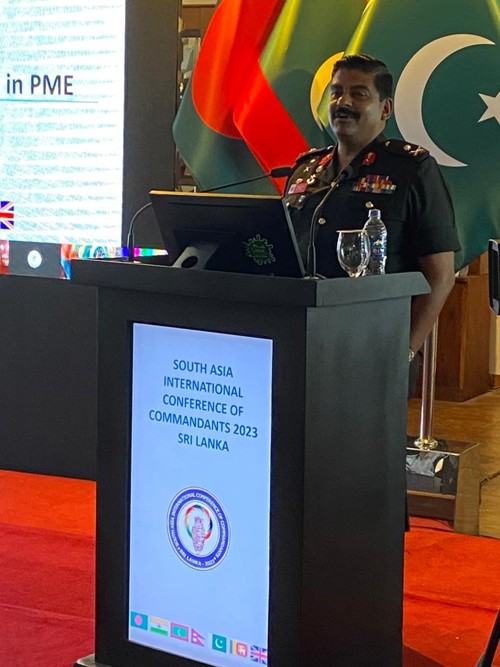 Commandant of Sri Lanka DSCSC giving a presentation surrounded by international flags.