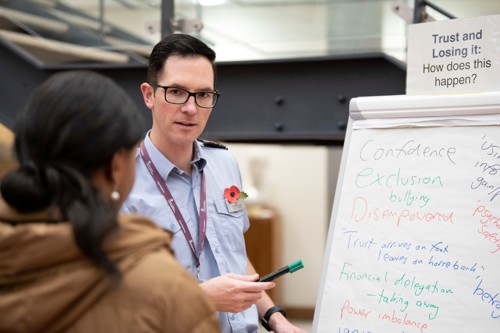 An RAF officer taking points from attendees to write on flip charts.