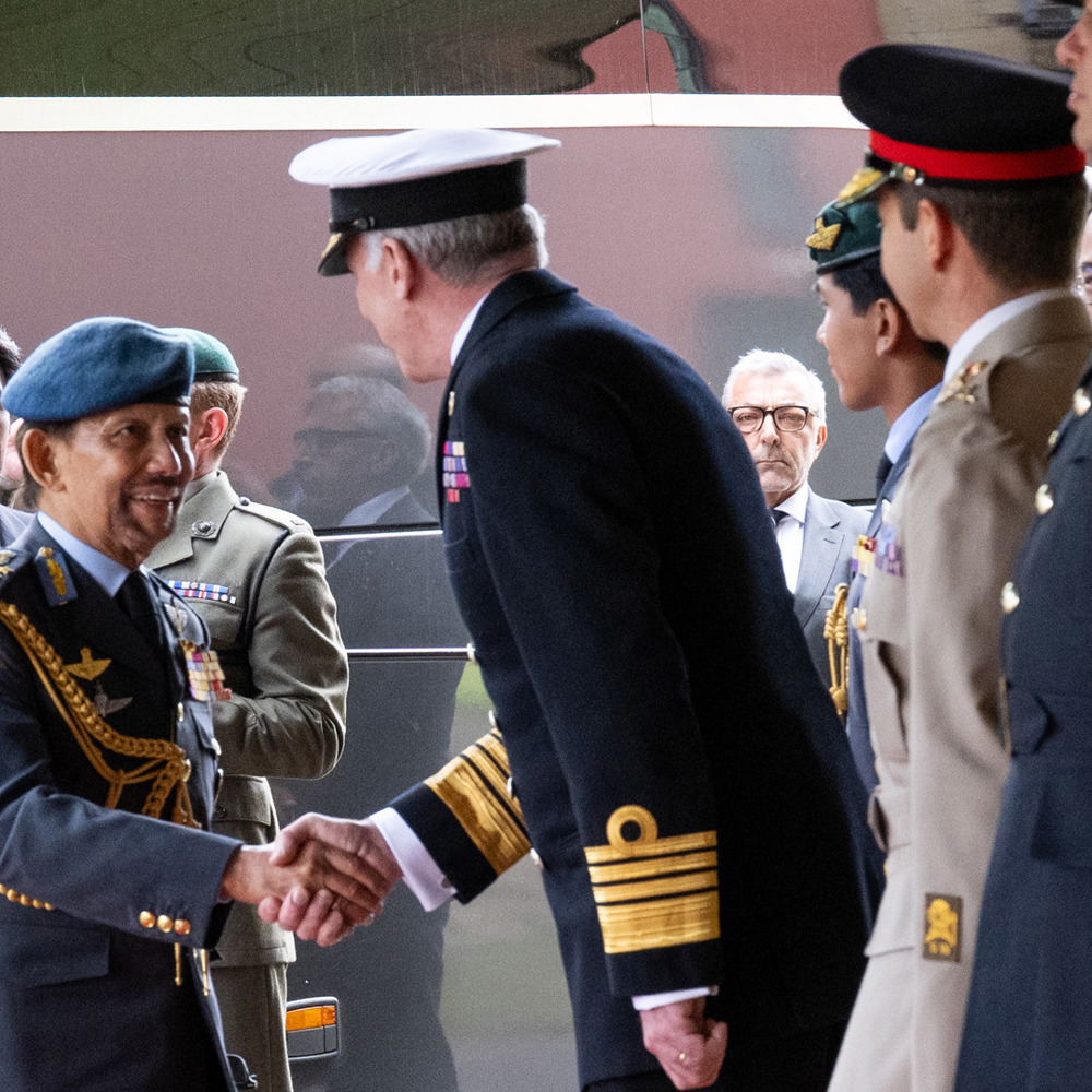 A senior British Navy officer greeting the Sultan of Brunei as he disembarked a coach.