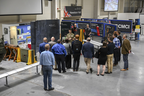 Visitors being given a talk surrounded by military equipment. 