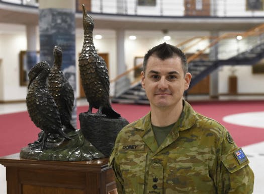 Australian Military officer stood next to Cormorant statue.