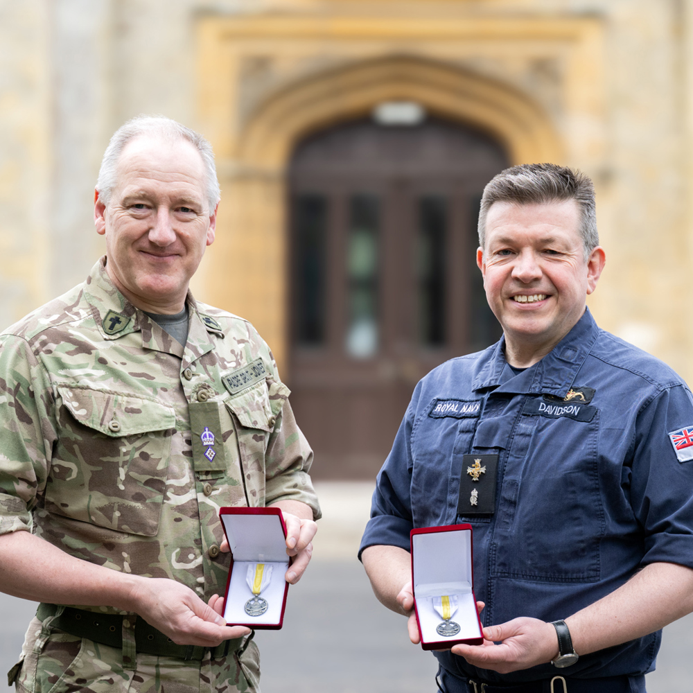 An Army and Navy padre holding their Ukrainian medals in their presentation boxes.
