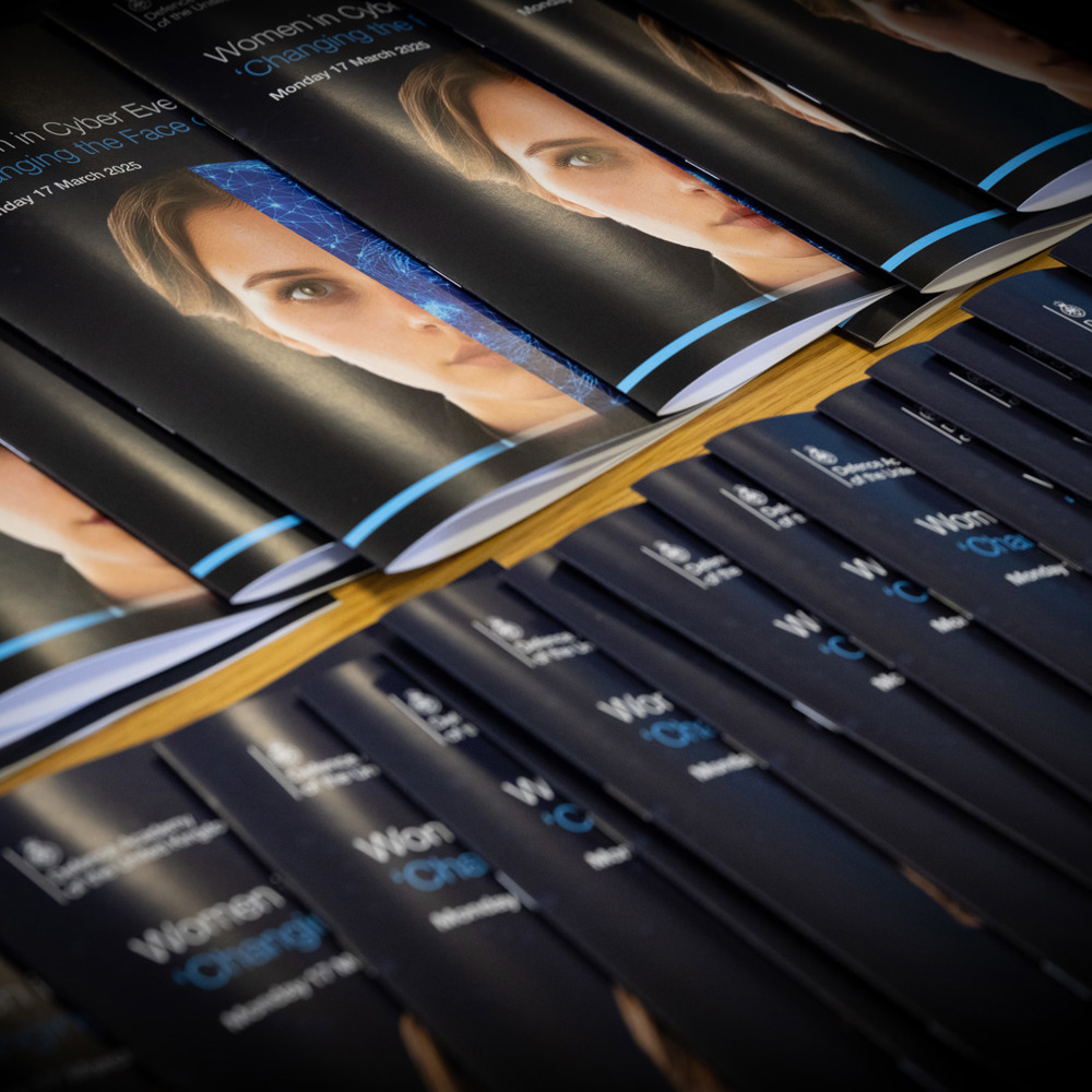 A row of 'Women in Cyber' leaflets overlapping.