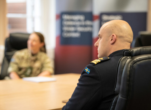 Over the shoulder of a Swedish officer showing the Swedish flag on his uniform.