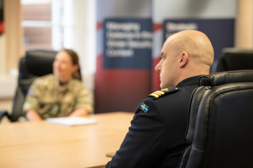 Over the shoulder of a Swedish officer showing the Swedish flag on his uniform.