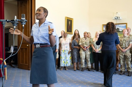Female RAF officer singing with rest of choir in the background.
