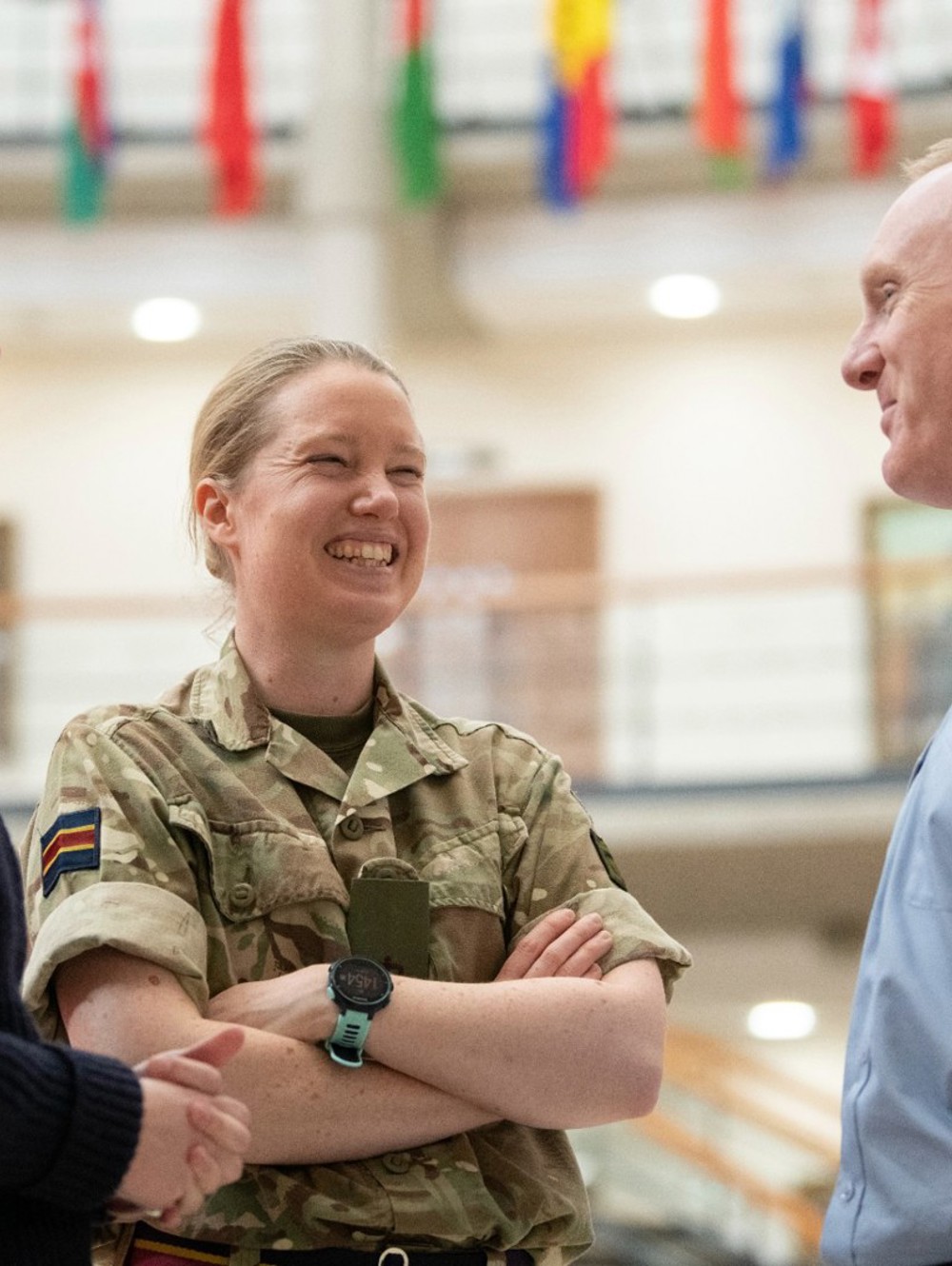 Three people in RAF, Navy and Army uniform smiling and talking in a small group