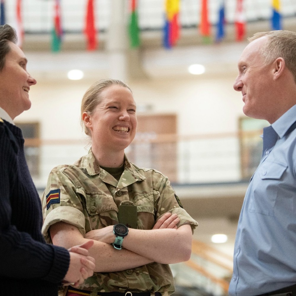 Three people in RAF, Navy and Army uniform smiling and talking in a small group