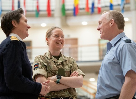 Three people in RAF, Navy and Army uniform smiling and talking in a small group