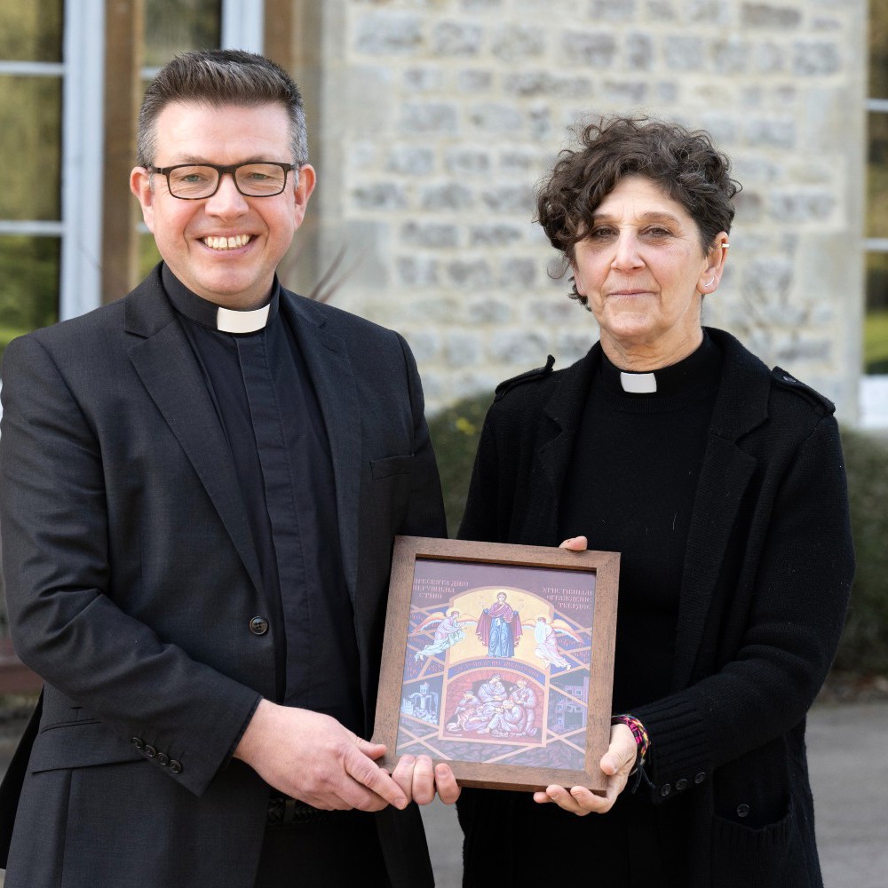 a female and Male Reverand holding a religious artwork.