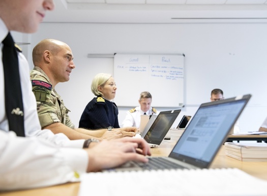 Students in Service uniform seated in a classroom working on laptops