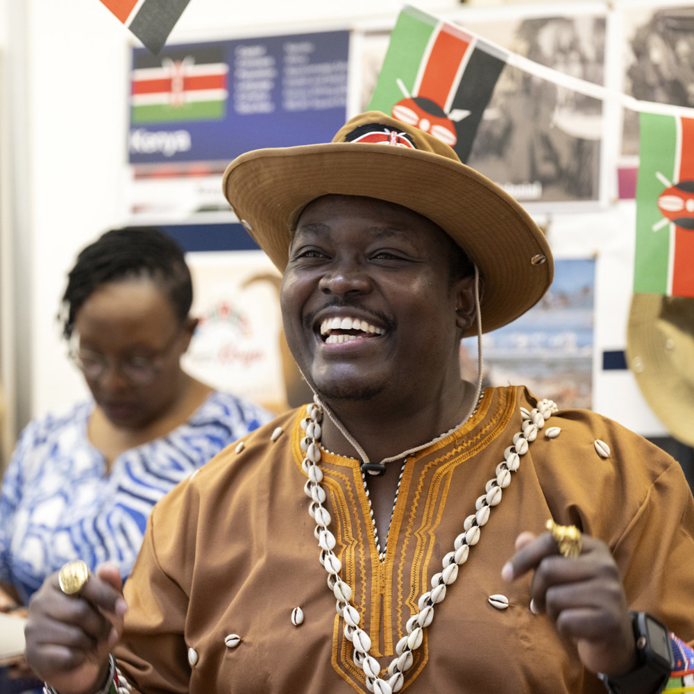 A black man wearing national dress while smiling. 