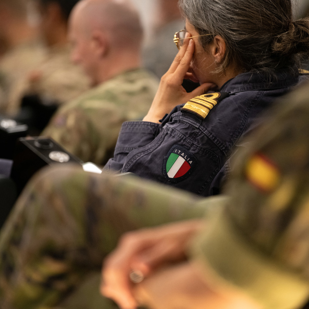 A side close shot of a women in a Navy uniform showing an Italy badge on her arm. 