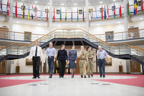 Tri-service personnel walking through the Forum with international flags hanging above them.