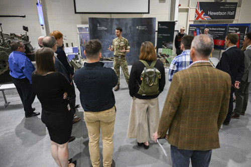 Visitors being given a talk surrounded by military equipment. 