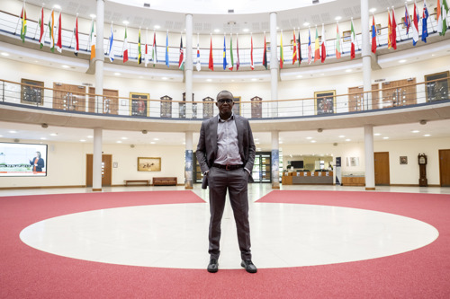 Ghanaian librarian stood in the Forum, Cormorant Building surrounded above by international flags. 