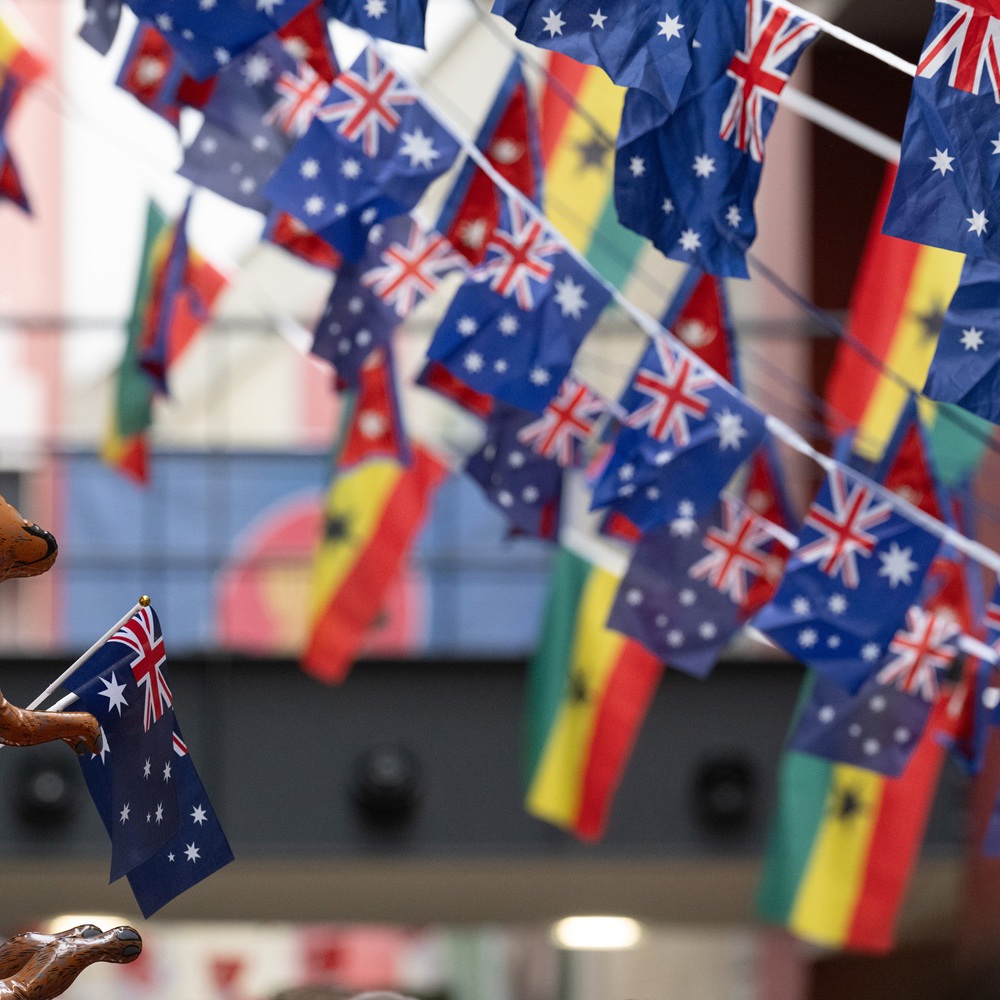 Rows of Australian flags hanging above a street with a inflatable kangaroo holding a small Australian flag in the foreground.