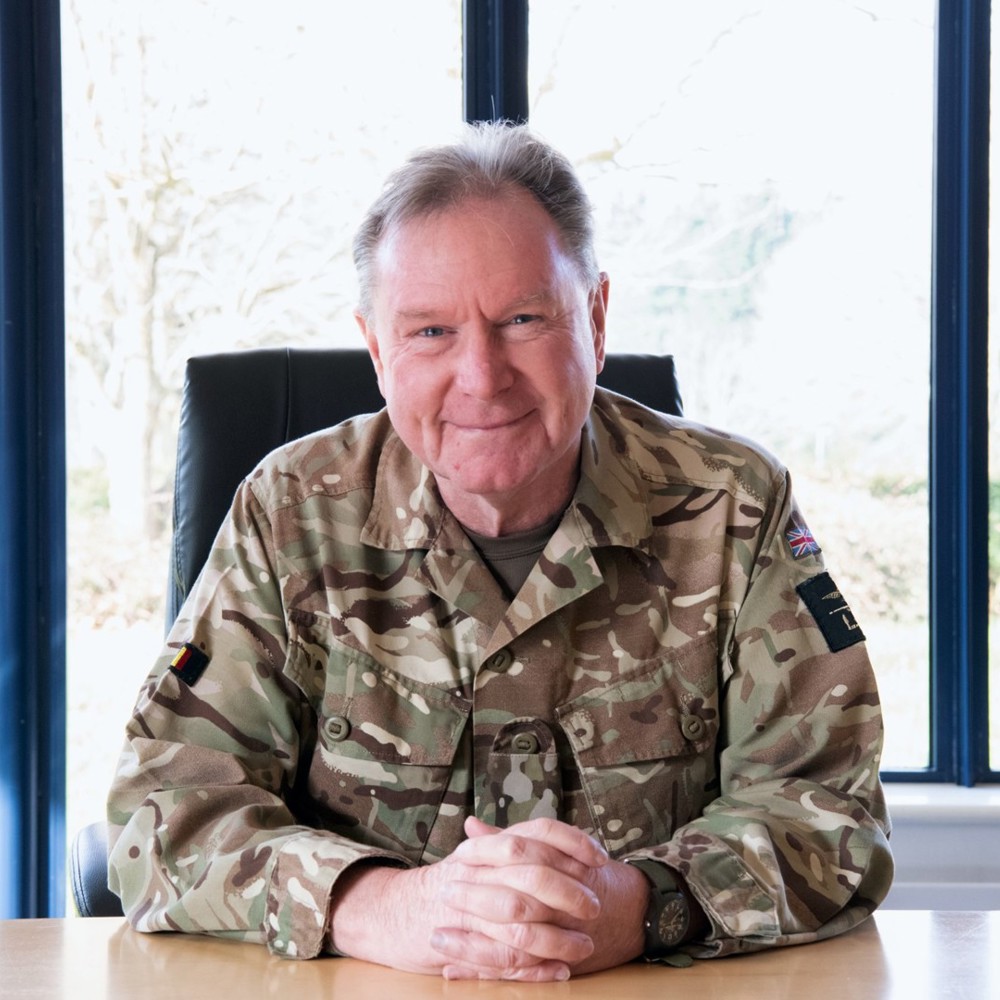 A British Army officer sat in a conference room on a leather chair leaning onto the desk.
