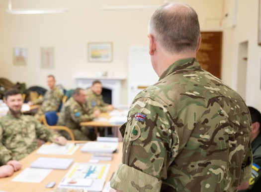 A UK army officer teaching a classroom of military officers.