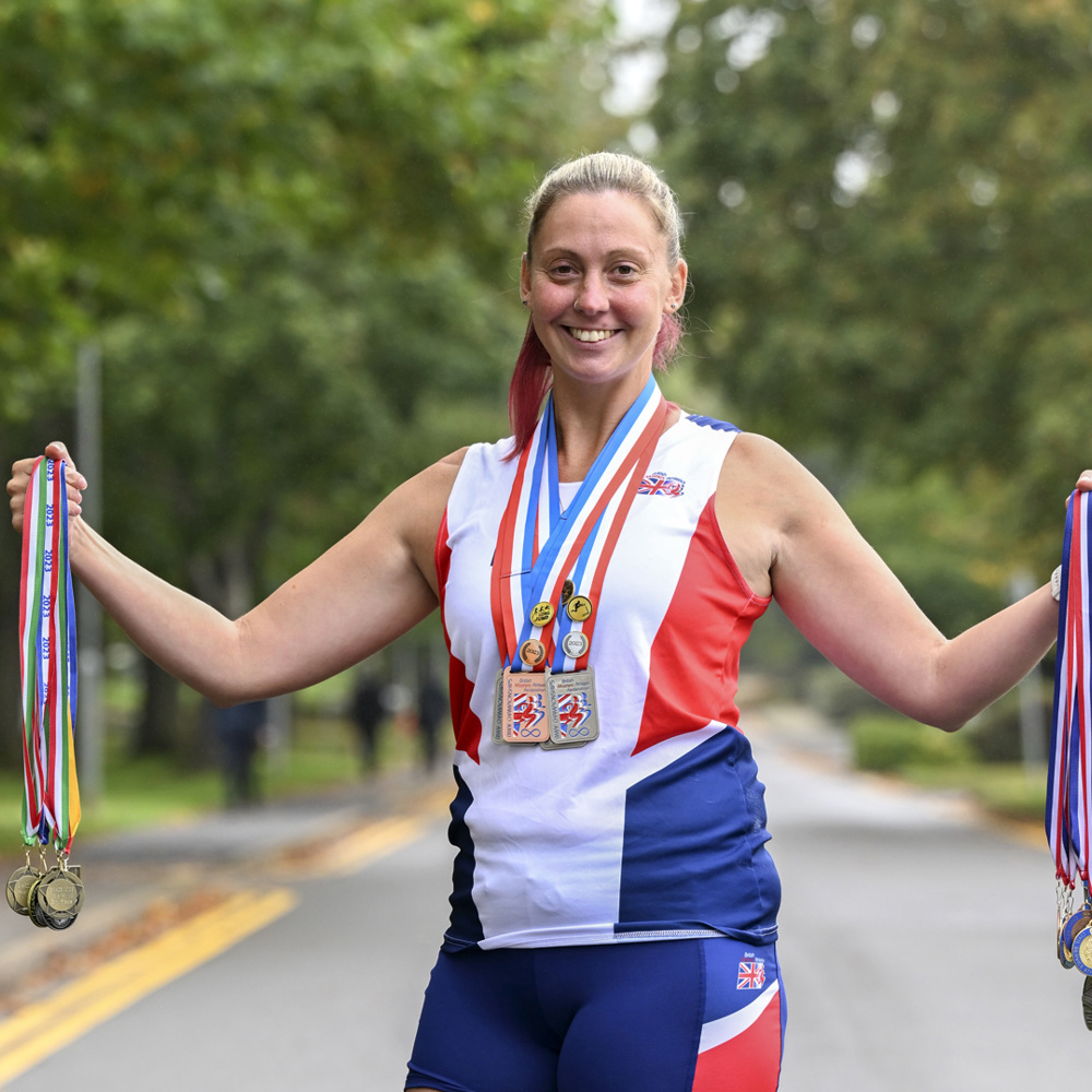 A women stood outside holding up her European Athletics medals.