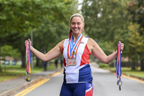 A women stood outside holding up her European Athletics medals.