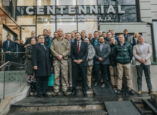 A mixture of people stood in military and civilian clothing outside the Centennial building in Finland. 