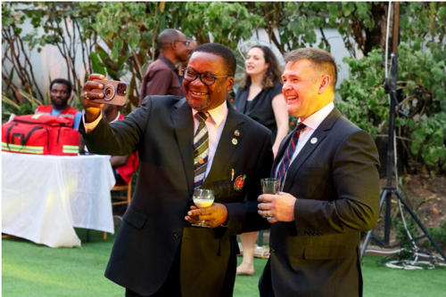 Two men in suits smiling taking a selfie.