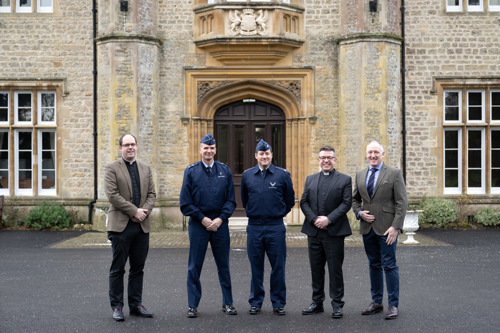 Military Padres and US Air Force officers stood outside an impressive stone grade 2 listed building with a large double wooden door behind them.