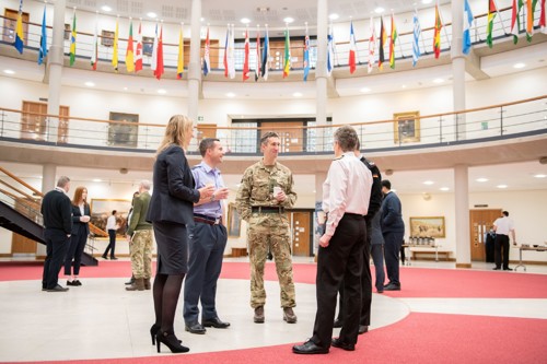 whole force staff gathered in the Forum drinking coffee surrounded by international flags.