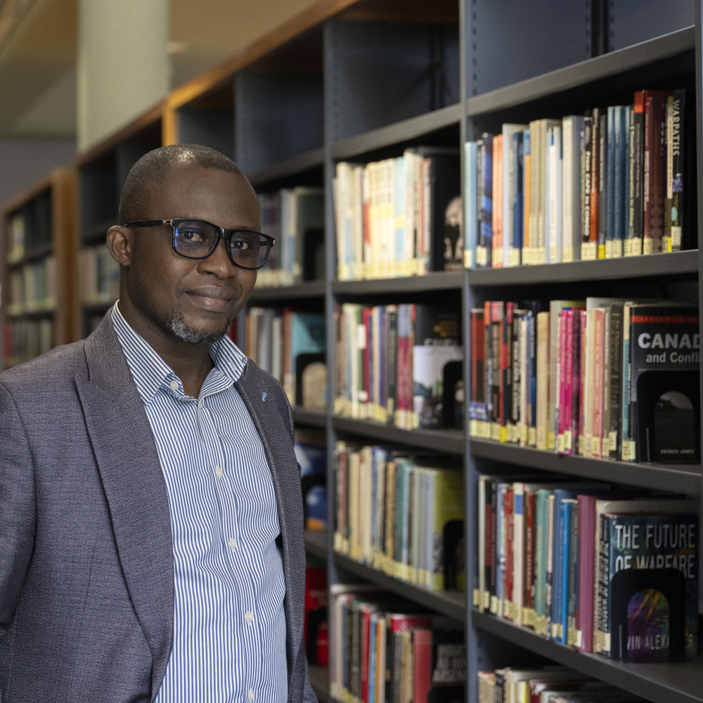 A person led against a large bookcase inside a library. 