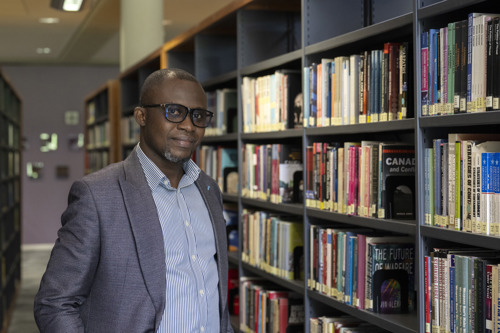 A person led against a large bookcase inside a library. 