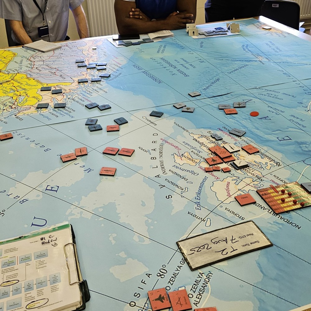 Players strategize over a detailed naval warfare board game map with red and blue unit tokens spread across the North Sea and surrounding areas.