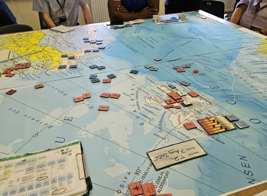Players strategize over a detailed naval warfare board game map with red and blue unit tokens spread across the North Sea and surrounding areas.