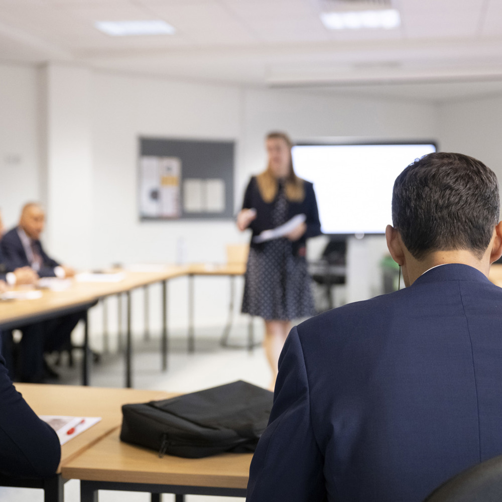 Students in a classroom being spoken to by instructor. 