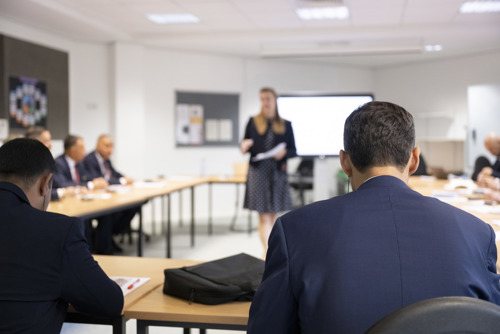 Students in a classroom being spoken to by instructor. 